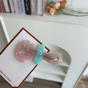 Fermaglio per capelli in acetato rosa marmo e verde menta con strass a cuore su carta