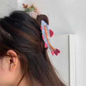Detail showing the polished marble texture of blue fish hair claw clip on wavy hair