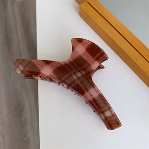 Detail view of large hair claw clip featuring classic red and brown plaid pattern