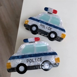 Detail view of two acetate police car hair claws with blue and white polished textures