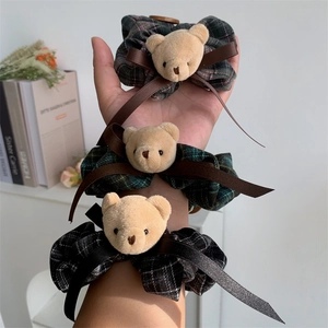 Detail showing three plaid scrunchies with plush bear heads and satin bows on arm