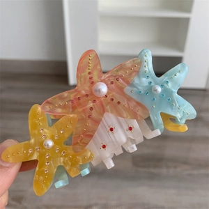 Close-up of starfish hair claws with marble texture, pearls and sparkling crystals