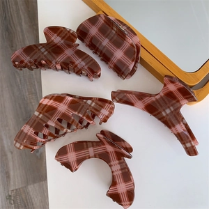 Detail view of five large acrylic hair claws in vintage coffee and pink plaid patterns