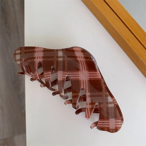Detail of a large shark hair claw clip featuring a classic brown and beige plaid pattern