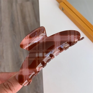 Detailed view of a large brown plaid hair claw clip with sturdy spring mechanism