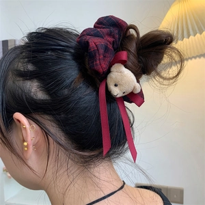 Close-up of a plaid hair scrunchie with a cute plush bear and bow on a girl hair