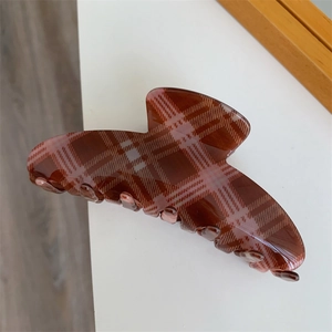 Detail of large red and white plaid hair claw clip made of glossy resin material