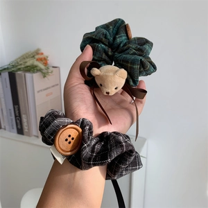 Detail of plaid fabric scrunchies with cute plush bear and vintage button accents