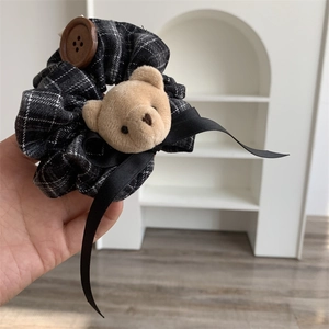 Detail of black plaid scrunchie with cute bear plush button and elegant black ribbon