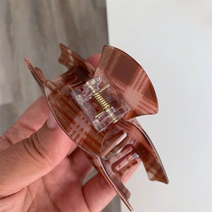 Close-up of a large brown checkered hair claw clip with a strong metal spring mechanism