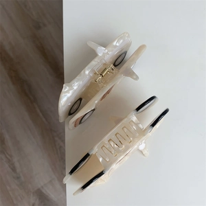 Detail of white pearlescent car-shaped acetate hair claw with visible golden metal spring