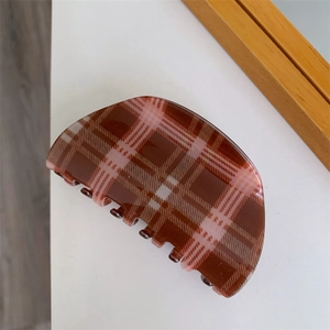Macro shot of semi-circular hair claw clip featuring classic brown plaid pattern