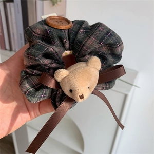 Detailed close-up of plaid scrunchie with plush bear head and wooden button detail
