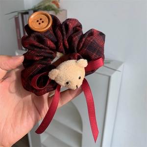 Close-up of red plaid scrunchie with teddy bear head and wooden button detail