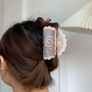 Detail view of pink and iridescent wave edge hair claw with shell pattern and rhinestone