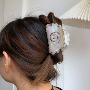 Elegant medium acetate shark hair claw with iridescent white finish and rhinestone on hair bun