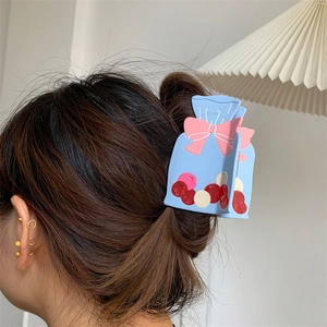Pince à cheveux en acétate forme sac cadeau avec nœud rose sur un chignon
