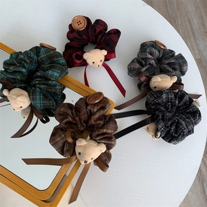 Detail of plaid fabric scrunchies with plush bears and vintage wood buttons on a white table
