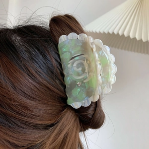 Detailed view of bicolor acetate hair claw clip with scalloped edges on brunette hair