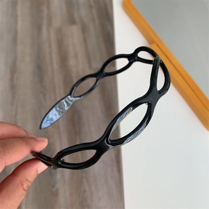 Close-up of a glossy black acetate headband with modern geometric hollowed-out link design