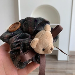 Detail of plaid scrunchie with plush bear head, wooden button and brown ribbon