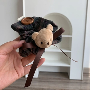 Detailed shot of dark green plaid scrunchie with plush bear, wooden button and satin ribbon