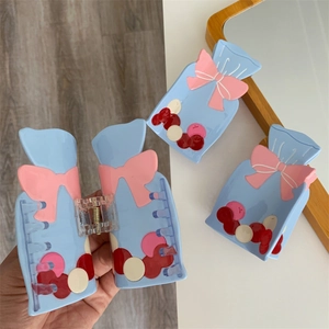 Vue détaillée de trois pinces à cheveux bleues en acétate avec nœuds roses et pois colorés