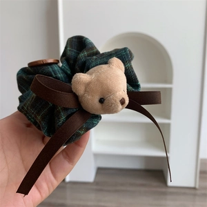 Detail of plaid scrunchie with plush bear head and wooden button decoration