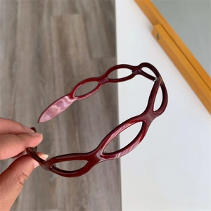 Detail showing the burgundy hollow oval chain pattern and glossy texture of the headband