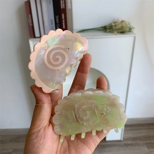 Detail of pink and green acetate shark hair clips with scalloped edges and rhinestone accents