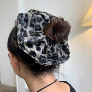 Detail shot of a stylish leopard print faux leather hair scrunchie worn on a hair bun