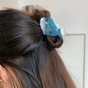 Détail d'une pince à cheveux baleine en acétate bleu nacré sur une coiffure mi-haute