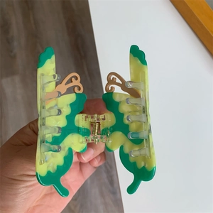 Detail of butterfly hair claw clip with green and yellow marble patterns and metal spring