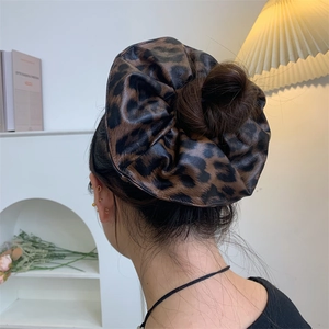 Close-up of large leopard print PU leather hair scrunchie worn on a back bun hair style