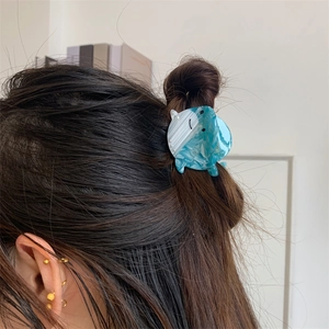 Pince à cheveux baleine en acétate marbré bleu présentée dans un chignon