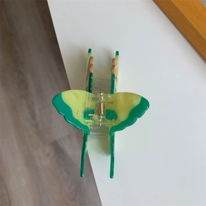 Macro detail of butterfly hair claw clip with green and yellow acrylic finish and gold spring