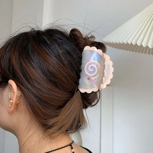 Detail of acetate shell claw clip with pearl finish and crystal on brunette hair