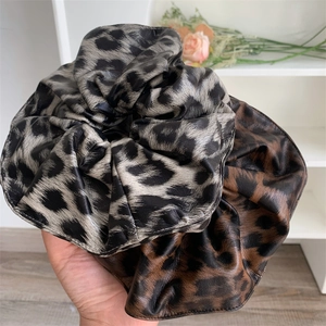 Detail shot of leopard print faux leather scrunchies showing texture and subtle gloss