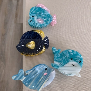 Détail des pinces à cheveux en acétate forme baleine et poisson avec perles et marbrures