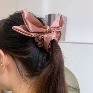 Detail of dusty pink satin hair scrunchie with a large bow worn on a long ponytail