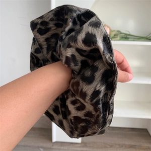 Detail of oversized leopard print hair scrunchie with soft faux leather texture on wrist