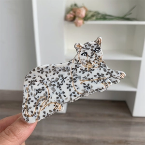 Detailed close-up of a leopard-shaped acetate hair claw clip held in hand for hair styling