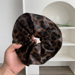 Detailed view of leopard print faux leather scrunchie with stylish ruched texture