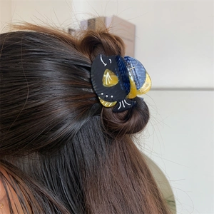 Détail d'une pince à cheveux baleine en acétate avec perles sur de longs cheveux bruns