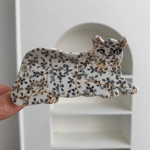 Detail shot of a leopard-shaped acetate hair claw with white snow leopard spots and gold edges