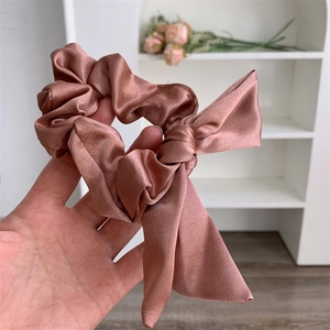 Detail of rose gold satin bow scrunchie showing silky texture and elegant fabric folds