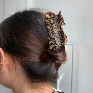 Detail view of large leopard-shaped acetate claw clip styled in a real hairstyle