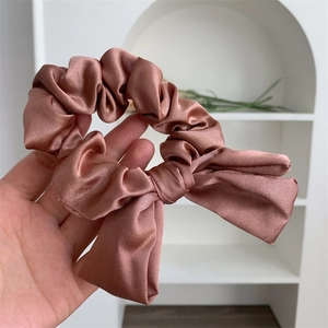Detail of elegant satin bow scrunchie in dusty rose color with premium silk-like texture