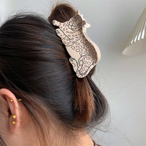 Detail of a leopard-shaped acetate hair claw clip with brown animal spots in apricot