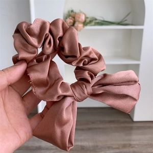 Detailed macro view of the silky ribbon bow scrunchie in elegant rose pink fabric